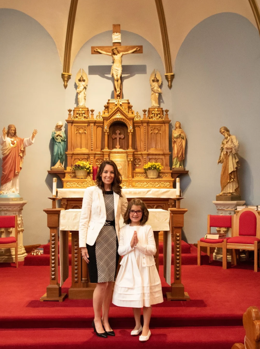 Amanda and her daughter in a Catholic Church standing in front of an altar